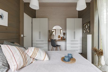 Cozy wood-paneled bedroom with built-in cabinets, arched alcove, and rustic decor.