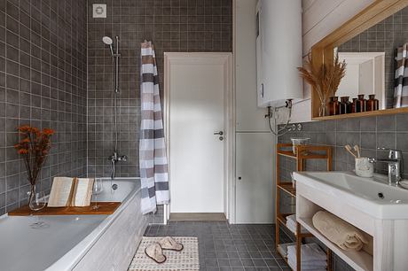 Sleek, modern bathroom with gray tile, wooden accents, and open shelving.