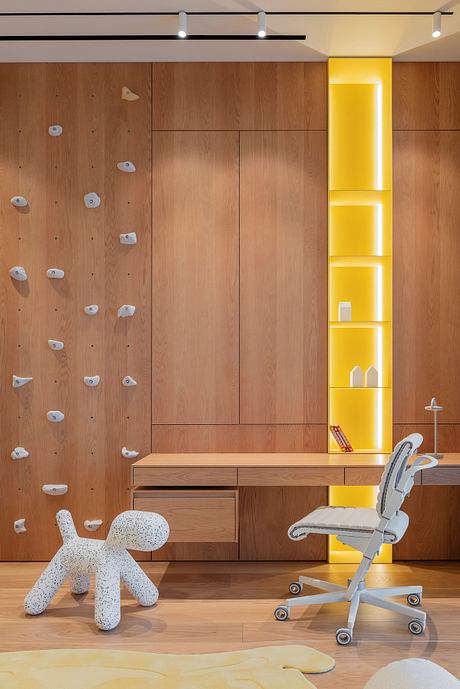 A modern, wood-paneled room with a yellow accent wall, a climbing wall, and a stylish office chair.