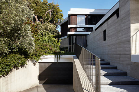 Modern concrete building with wooden accents, steps, and lush vegetation surrounding the structure.