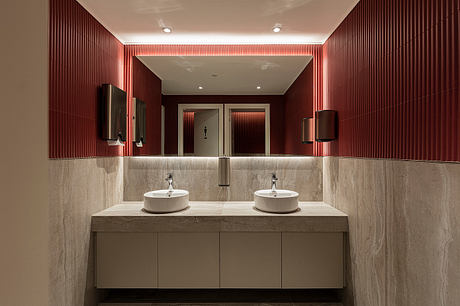 Luxurious bathroom with red-paneled walls, double vanity, and modern fixtures.