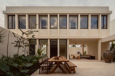 A modern, minimalist villa with a large open-plan living area and dining terrace.