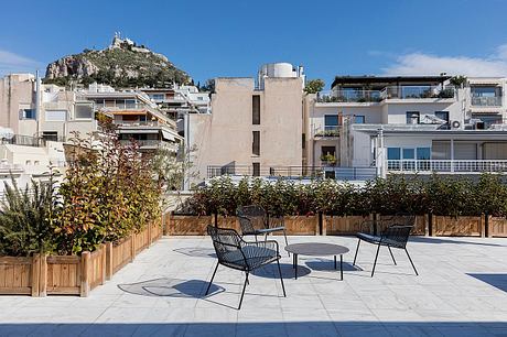 Sleek urban terrace with modern patio furniture, lush greenery, and views of the surrounding architecture.