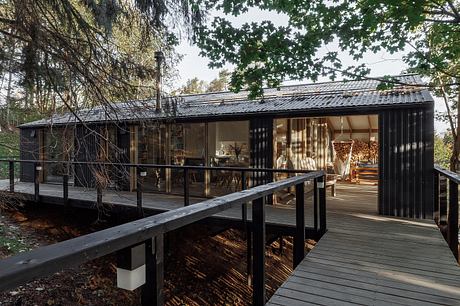 A sleek, modern cabin with a wooden deck nestled among the trees, showcasing its architectural design.