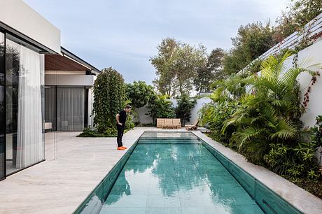 A modern backyard oasis with a sleek pool, lush greenery, and a cozy seating area.
