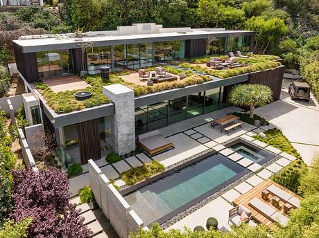 This modern architectural home features a lush, tiered garden with a sleek glass facade.