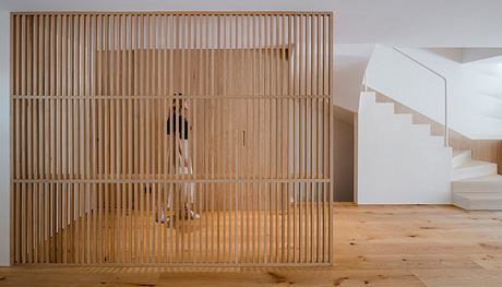 Minimalist wooden slat partition dividing the interior space, with a staircase visible.
