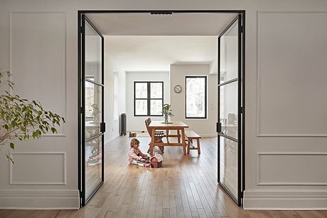 A spacious, modern living room with large windows, wooden floors, and a minimalist design.