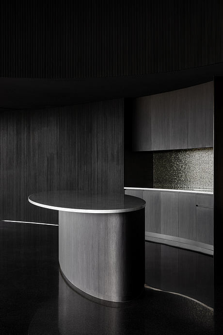 Striking black and white architectural design, with a sleek circular table and dark cabinetry.