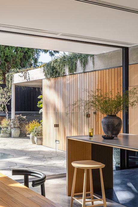 Sleek modern architecture with wooden panels, a kitchen island, and potted plants.