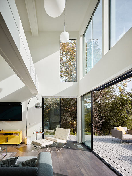 Spacious modern interior with floor-to-ceiling windows, wood floors, and sleek furniture.