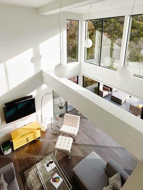 A modern, open-concept living space with floor-to-ceiling windows, minimalist furnishings, and natural lighting.