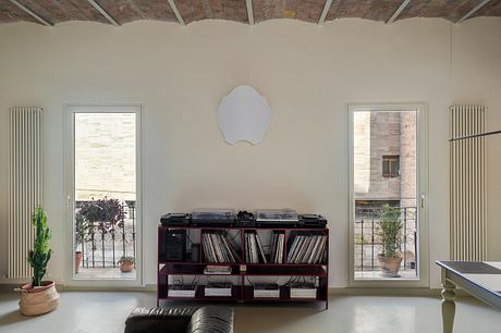 Minimalist living space with brick ceiling, large windows, and a record player stand.