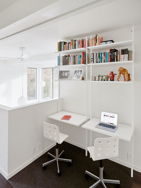 A cozy home office with built-in bookshelves, modern furniture, and large windows.