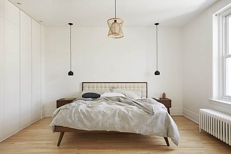 Cozy, minimalist bedroom with wooden furniture, pendant lights, and plush bedding.