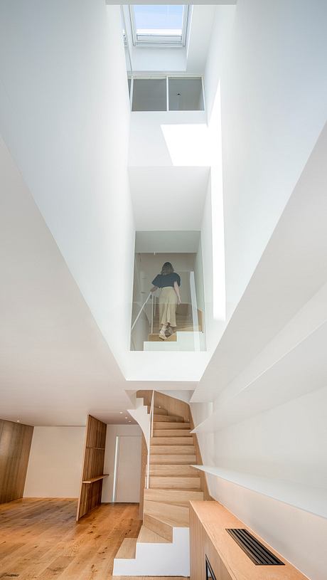 A bright, open-plan interior with a striking wooden staircase leading to an upper level. Ample natural light illuminates the space.