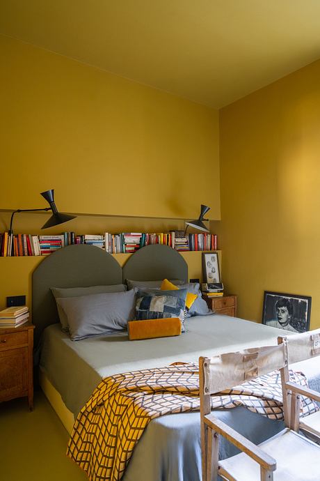 A cozy bedroom with colorful textiles, wooden furniture, and a bookshelf filled with books.