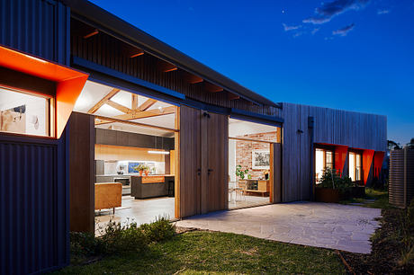 Striking modern architecture with large windows, wooden beams, and vibrant orange accents.