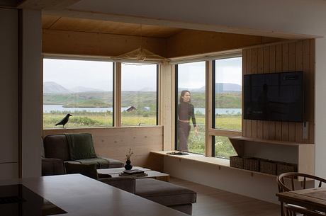 A cozy and rustic cabin interior with large windows overlooking a scenic landscape.