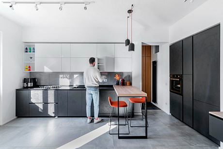 Modern kitchen with minimalist cabinetry, wooden table, and pendant lighting.