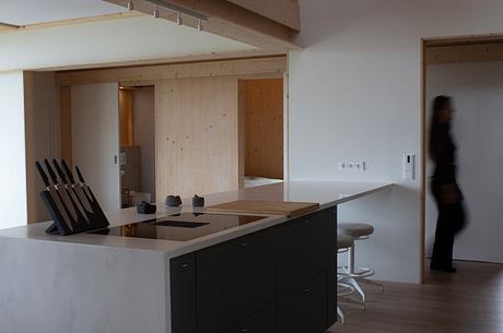 Modern open kitchen design with minimalist cabinetry, wooden accents, and sleek appliances.