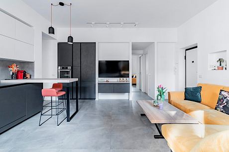 Modern open-concept apartment with sleek kitchen, living area, and wooden coffee table.