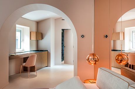 Elegant arched entryway leads to modern kitchen with warm orange accents and sleek furnishings.