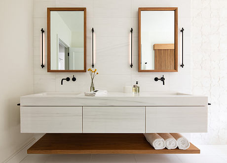 Elegant bathroom with floating vanity, warm wood accents, and minimalist mirrors.