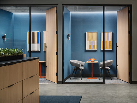 A modern office space with sleek blue walls, wooden furniture, and abstract art.