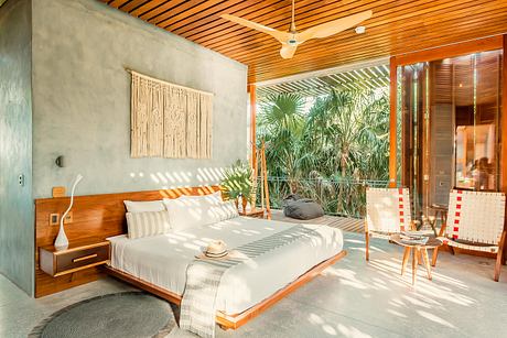Spacious, open-concept bedroom with wood-paneled ceiling, large window overlooking tropical foliage.