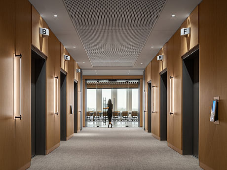 Modern office hallway with wooden accents, suspended lighting, and lettered doors.