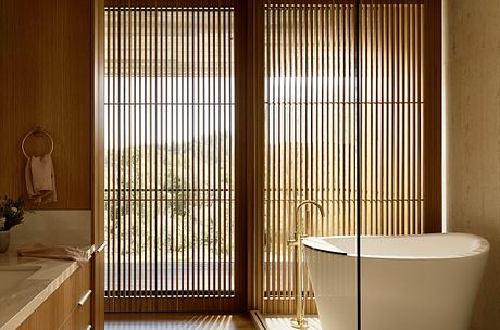 A modern bathroom with wooden slatted screens, a freestanding bathtub, and minimalist decor.