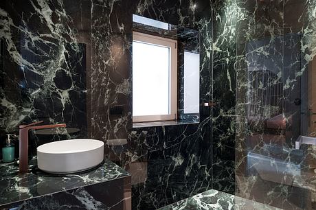 A luxurious bathroom with striking black marble walls, a vessel sink, and a large window.