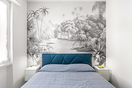 A vibrant tropical mural adorns the bedroom wall, complementing the blue upholstered headboard and bedding.