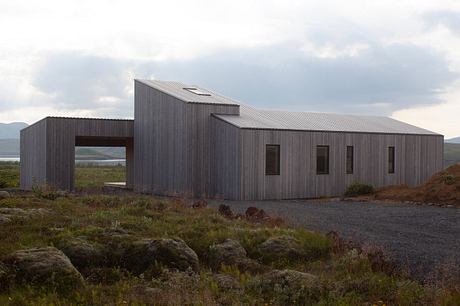 The building features a distinctive angular roof and wooden façade, blending into the rugged landscape.