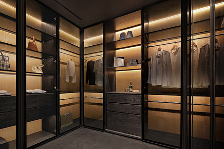 Sleek, modern closet with glass panels, dark wood drawers, and recessed lighting.