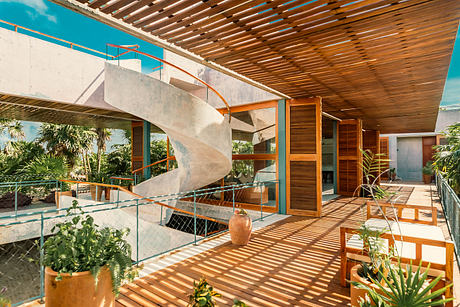 A modern tropical-style house with an open-air layout, featuring a spiral staircase and wooden beams.