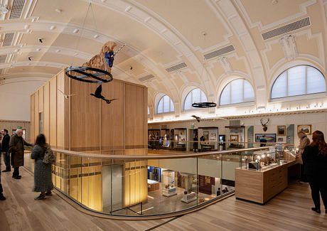 A grand, ornate lobby with arched windows, wooden accents, and suspended displays.