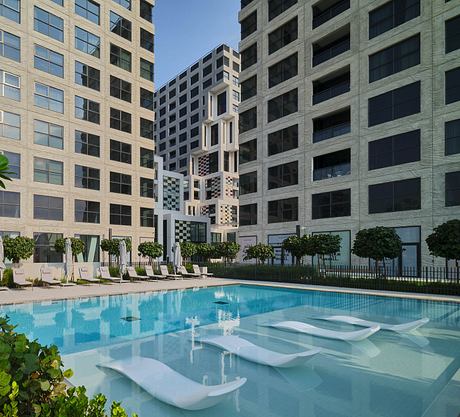 Sleek modern apartment complex with geometric facade and inviting pool area.
