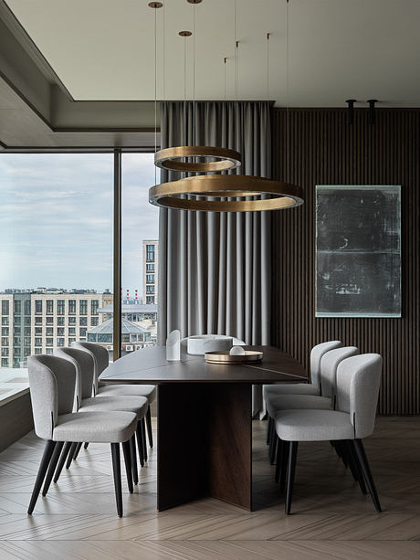 Elegant dining area with modern pendant lights, dark wood table, and plush gray chairs.