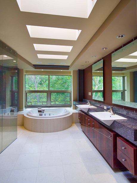 Expansive bathroom with large window, sunken tub, and wood vanity with granite countertop.