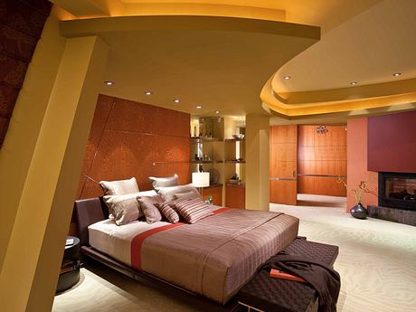 A modern, cozy bedroom with warm lighting, textured walls, and a sleek, low-profile bed.