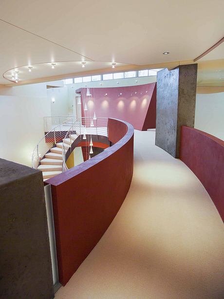 Striking architectural design featuring a curved, red staircase and muted tones.