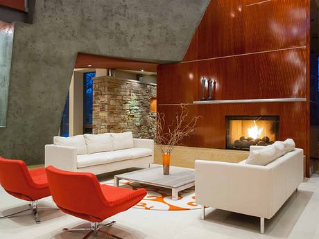 Striking modern living room with stone fireplace, sleek wood paneling, and tasteful furnishings.