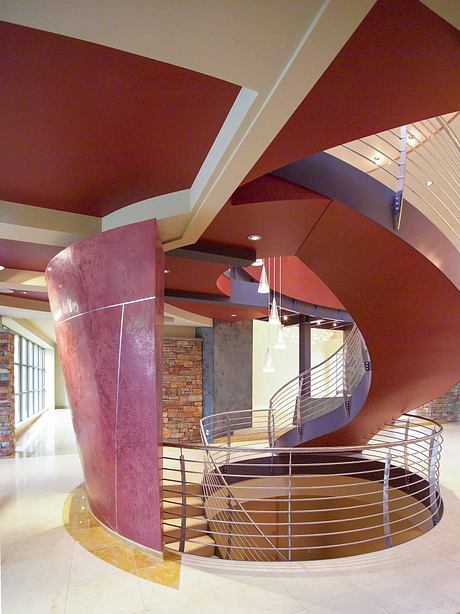 A modern, colorful architectural interior with geometric shapes, textured walls, and spiral stairs.