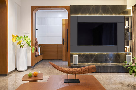 Modern living room with wooden accents, built-in TV display, and sculptural decorative elements.