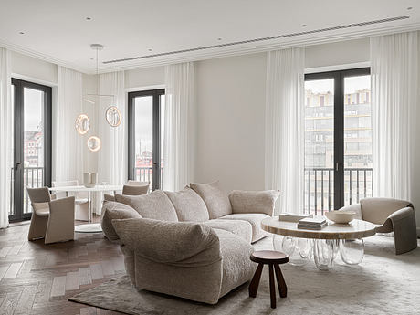 Spacious, minimalist living room with large windows, cozy sectional, and modern furnishings.