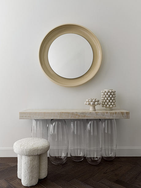 Minimalist interior design with a round mirror, wooden console table, and decorative spheres.