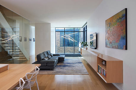 Spacious modern living area with large windows, sleek furniture, and vibrant artwork.