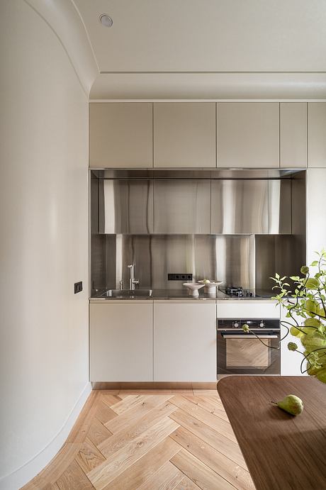 Minimalist kitchen with sleek cabinets, stainless steel appliances, and a wooden chevron floor.